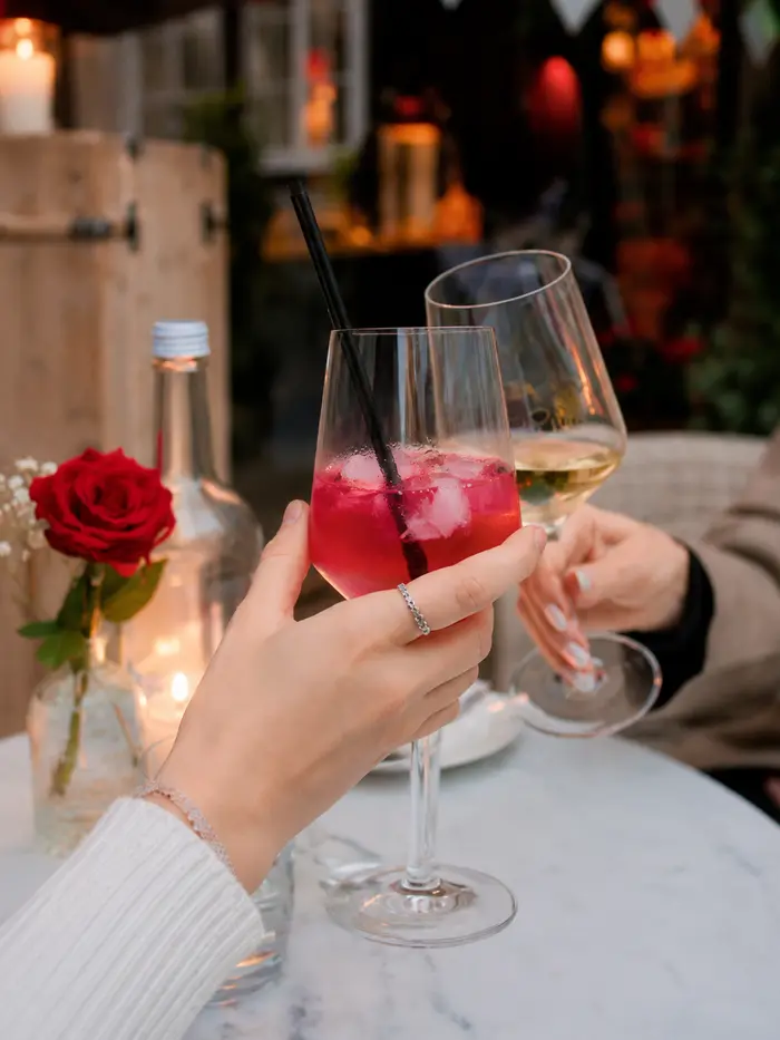 Zwei Gäste stoßen mit sommerlichen Drinks im Innenhof an
